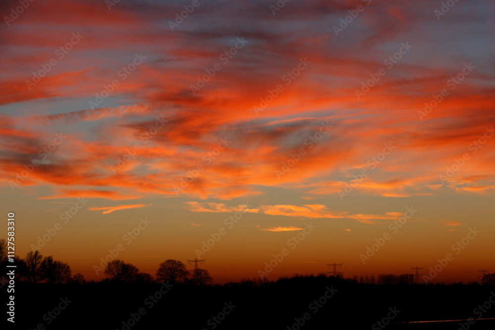 Vibrant sunset hues paint a dramatic sky, silhouetted trees and power lines. Warm colors and dark silhouettes. Vibrant sunset hues paint a dramatic sky, silhouetted trees and power lines. Warm colors and dark silhouettes.