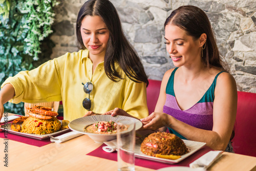 Latinx female friends together eating happy in a Ecuadorian food restaurant. Traditional meal photo