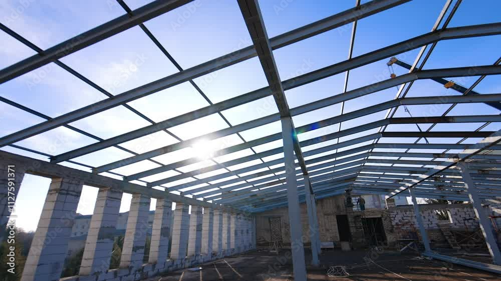 Sun beams go through the frame of the future roof. Man standing on the scaffolding applies welding apparatus. Low angle view. Sun beams go through the frame of the future roof. Man standing on the scaffolding applies welding apparatus. Low angle view.