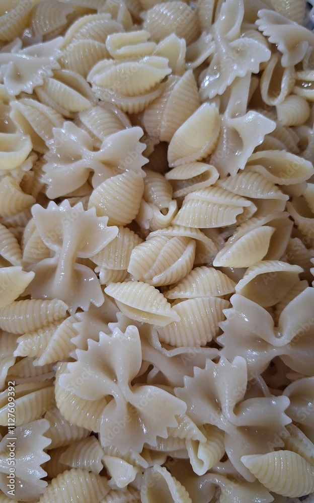 Background of wet pasta with butterfly and round designs. Close-up of pasta in a bowl showing its texture Background of wet pasta with butterfly and round designs. Close-up of pasta in a bowl showing its texture