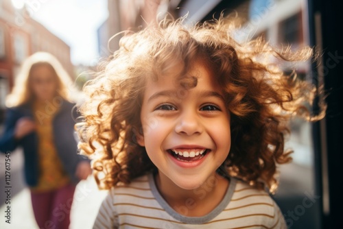 Close up portrait of a smiling little girl with curly hair in the city