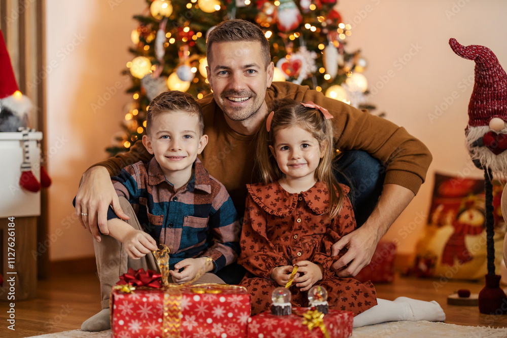 Portrait of lovely family hugging and smiling at camera at home decorated with christmas decorations.