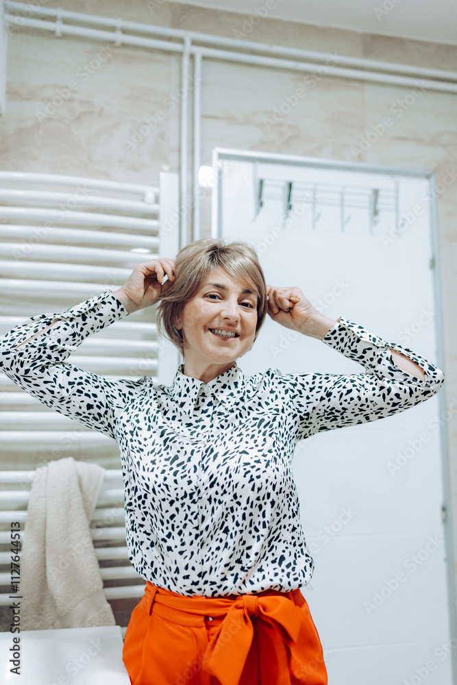 The woman exudes joy while playfully posing in her colorful outfit, capturing the essence of happiness and style in a warm, inviting setting near a bathroom. The woman exudes joy while playfully posing in her colorful outfit, capturing the essence of happiness and style in a warm, inviting setting near a bathroom.