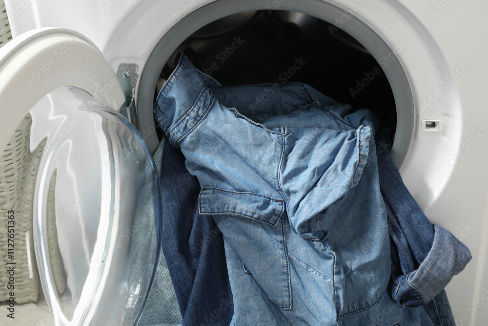 Washing machine with dirty jeans and other denim clothes indoors Washing machine with dirty jeans and other denim clothes indoors