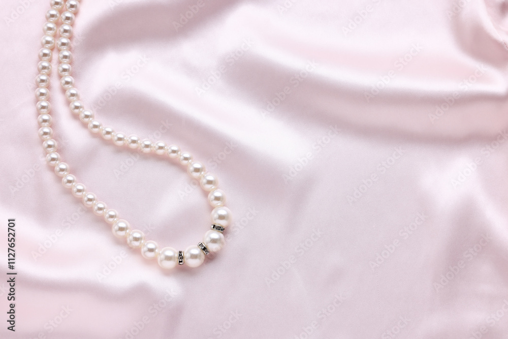 Elegant pearl necklace on pink fabric, top view. Space for text Elegant pearl necklace on pink fabric, top view. Space for text