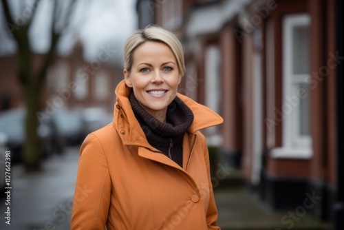 Portrait of a beautiful middle-aged woman in an orange coat on the street