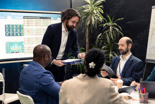 Project leader joins in a conference room with his management team to go over details on legislative shifts that might influence their duties. Director highlighting reports with collected data.