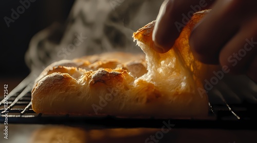 Hand tearing warm, freshly baked bread.