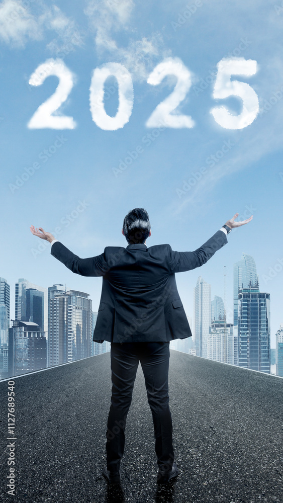 Rear view of businessman standing and looking at 2025 number on blue sky background Rear view of businessman standing and looking at 2025 number on blue sky background