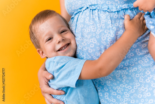 Motherhood, femininity, love, Childhood, hot summer - croped portrait pregnant unrecognizable woman blue dress little preschool boy son sibling hug mum big belly brother on yellow background copy