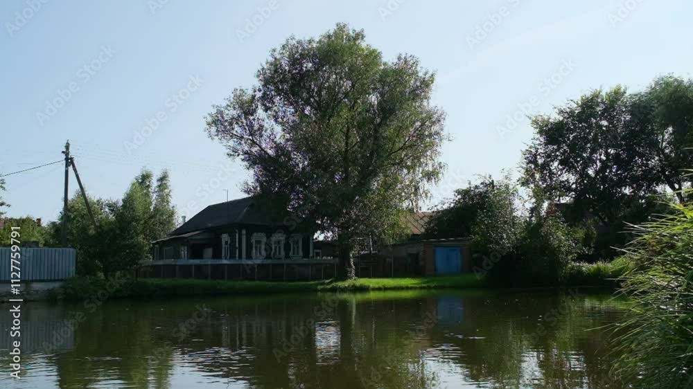 Moscow, Russia - Aug 20 2024: A serene view of a house by the lake in Ashitkovo village, surrounded by lush greenery and reflecting on calm waters Moscow, Russia - Aug 20 2024: A serene view of a house by the lake in Ashitkovo village, surrounded by lush greenery and reflecting on calm waters