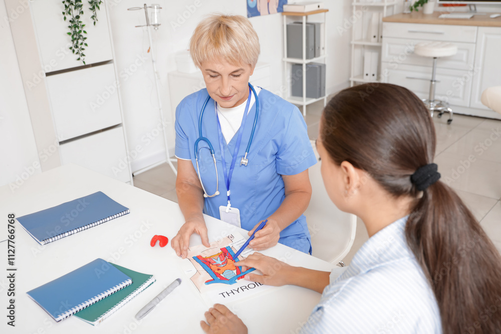 Female endocrinologist showing structure of thyroid gland to patient at table in clinic Female endocrinologist showing structure of thyroid gland to patient at table in clinic