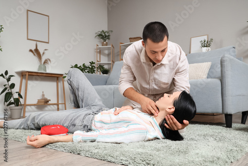 Young man checking pulse of...