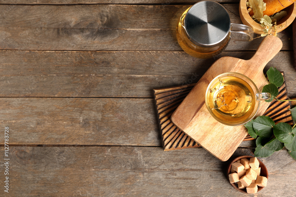 Cup and teapot of tasty linden tea with sugar cubes on wooden background Cup and teapot of tasty linden tea with sugar cubes on wooden background