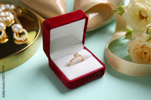 Engagement ring in box with bridal accessories on blue background photo