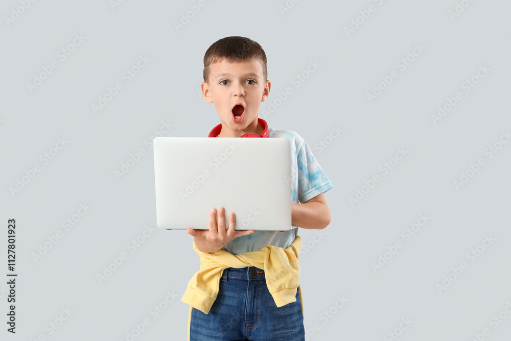 Shocked little boy using laptop on light background Shocked little boy using laptop on light background