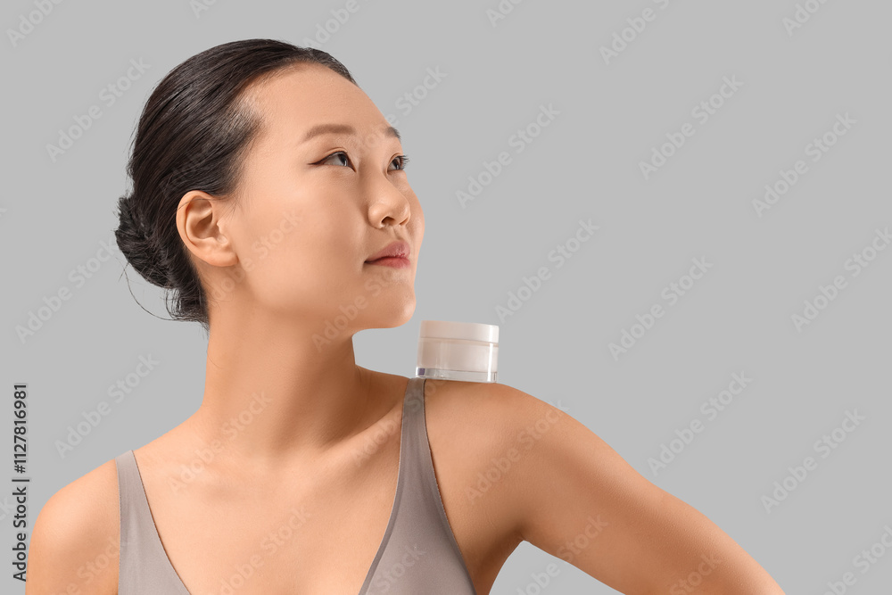 Young Asian woman with jar of cream on grey background, closeup Young Asian woman with jar of cream on grey background, closeup