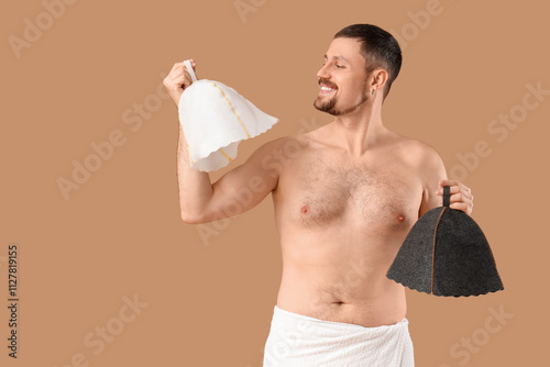 Handsome man with sauna felt hats on beige background photo