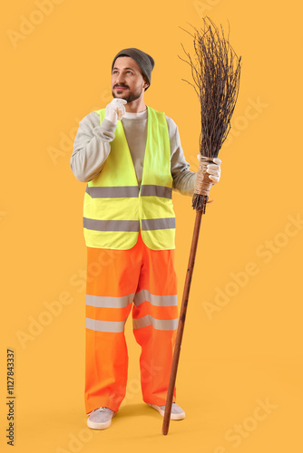 Thoughtful male scavenger with broom on yellow background photo