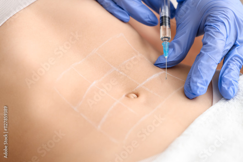 Young woman receiving injection in her belly at cosmetologist's office, closeup