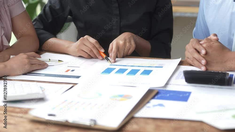 Three people are sitting at a table with papers and a calculator. They are discussing something important, possibly related to business or finance. The atmosphere seems serious and focused Three people are sitting at a table with papers and a calculator. They are discussing something important, possibly related to business or finance. The atmosphere seems serious and focused