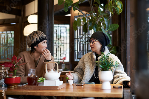 two fashion Asian ladies having conversation in traditional Chinese tea house