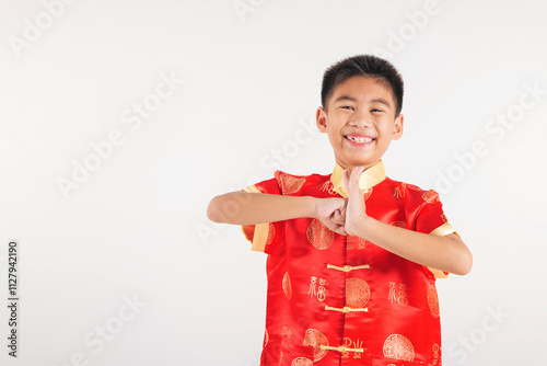 Happy Chinese New Year Smiling Asian boy in a traditional red cheongsam qipao dress makes a congratulatory gesture, symbolizing blessings and good fortune. festive themes