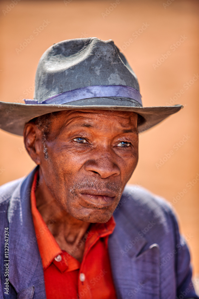 village single african old man with a hat portrait, outside i the yard at his home