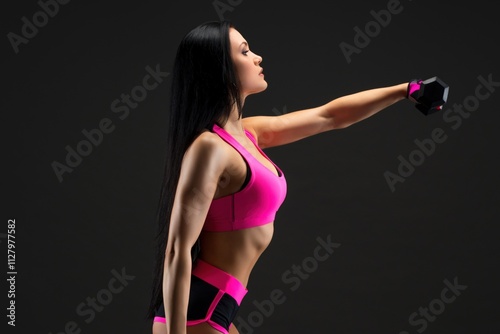 Brunette exercising with dumbells against gray background photo