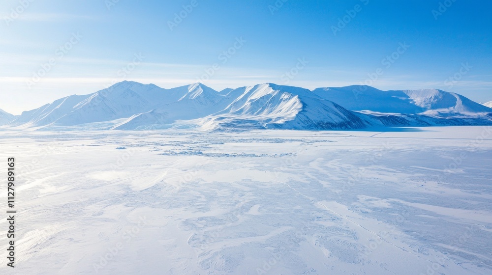 An aerial view captures the serene beauty of Arctic winter, highlighting majestic snow-covered mountains and a glistening icy landscape under a bright blue sky An aerial view captures the serene beauty of Arctic winter, highlighting majestic snow-covered mountains and a glistening icy landscape under a bright blue sky