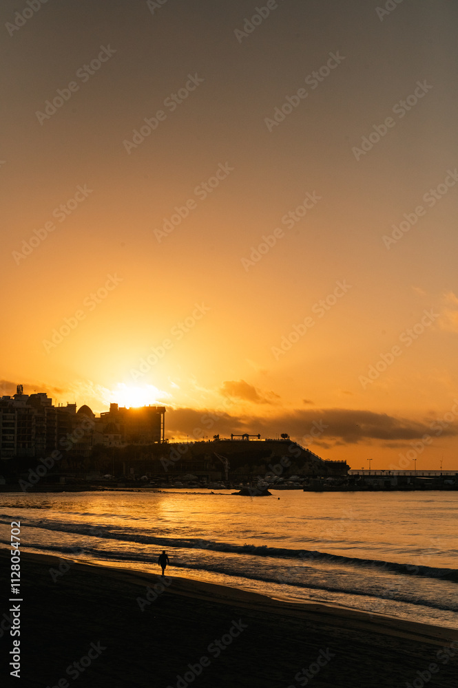 People walking in te beach whit the Sunrise in the tourist city of Benidorm in Alicante, Spain in 2024.