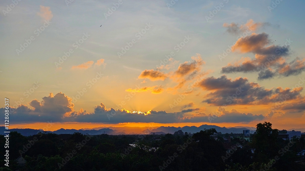 Fototapeta premium A breathtaking sunset paints the sky with hues of orange, pink, and purple, casting a warm glow over the distant landscape and creating a sense of tranquility. 