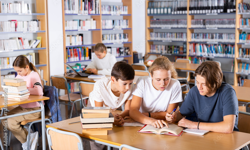 Teenage students working in groups in college library Teenage students working in groups in college library