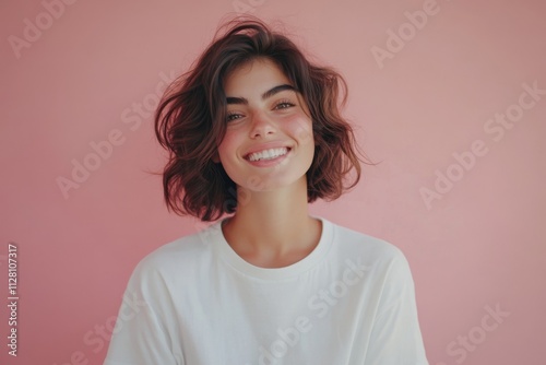 Portrait of a beautiful young woman in a white t-shirt against a pink background.