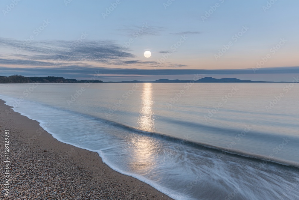 Obraz premium Serene beach at sunrise with calm waters and distant hills.