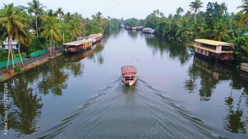 Kumarakam world tourism ,Aerial view of Kerala's backwaters with rows of houseboats lined up and a small boat sailing through the water nearby photo