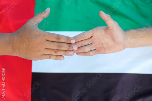 Close Up of Two Hands Touching Each Other Against UAE National Flag Background photo