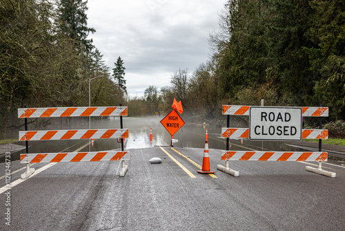 Signs and cones at a road barricade. Street of HIllsboro closed due to high water after a rainfall