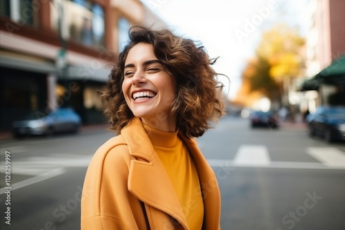 Portrait of a beautiful young woman laughing on the street in autumn