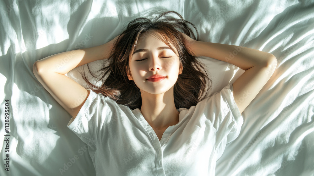 Naklejka premium young Asian woman lies comfortably on her bed, enjoying peaceful moment with serene expression, surrounded by soft white sheets