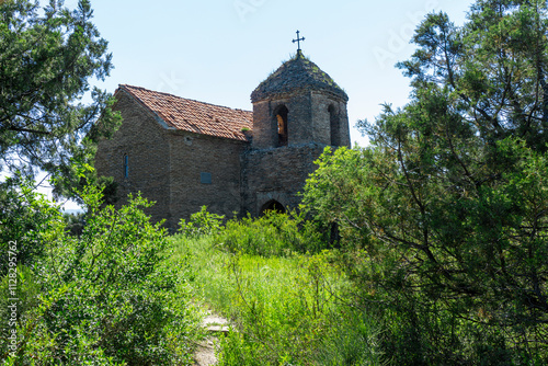The small church on the hill among bushes and trees is part of the Shio-Mgvime monastery. The bright blue sky in the background. photo