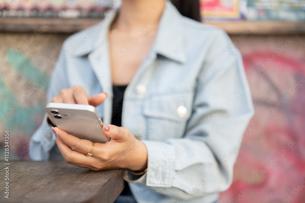 A close-up of a woman sits at an outdoor table of a cafe, using her smartphone, reading messages. A close-up of a woman sits at an outdoor table of a cafe, using her smartphone, reading messages.