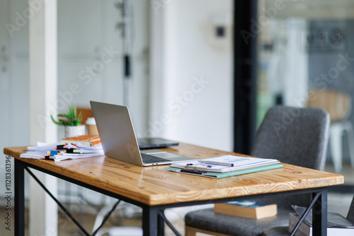 Foto Laptop Computer, notebook, and eyeglasses sitting on a desk in a large open plan