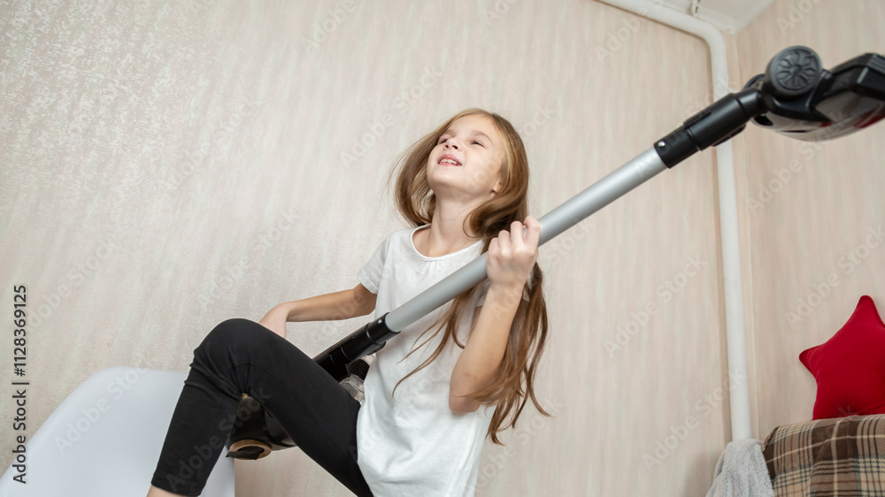 Child imitating playing guitar with vacuum cleaner in living room Child imitating playing guitar with vacuum cleaner in living room