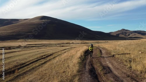 Lone female backpacker hikes thru remote grassland plateau in Georgia photo