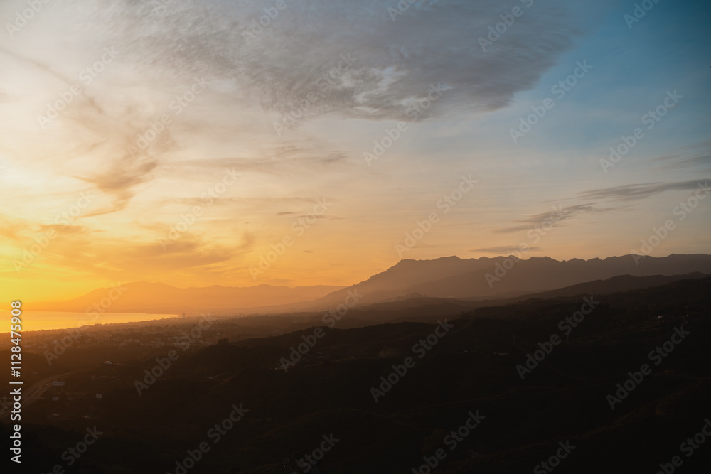 Softly lit hills and distant mountains under a golden sunset, creating a peaceful natural landscape Softly lit hills and distant mountains under a golden sunset, creating a peaceful natural landscape