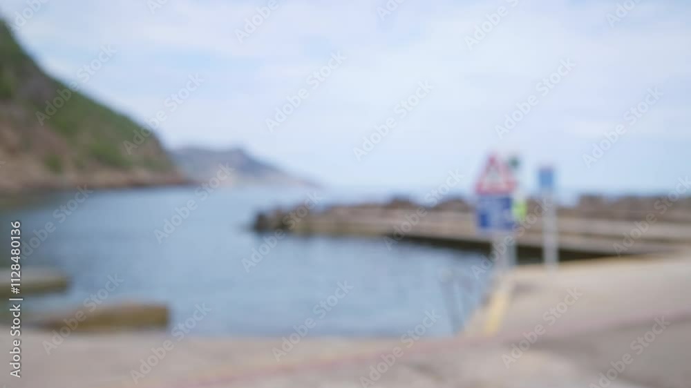 Blurry scenic view of mallorca coastline with a defocused dock, sea, and signs in the background Blurry scenic view of mallorca coastline with a defocused dock, sea, and signs in the background
