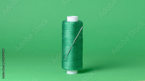 Green thread spool with needle close-up flat lay top view background with copy space for text photo