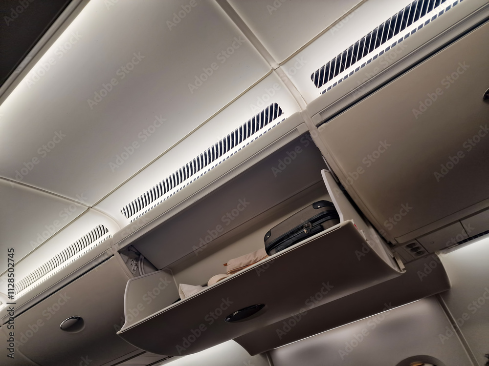 Open overhead compartment with suitcases on the plane Open overhead compartment with suitcases on the plane