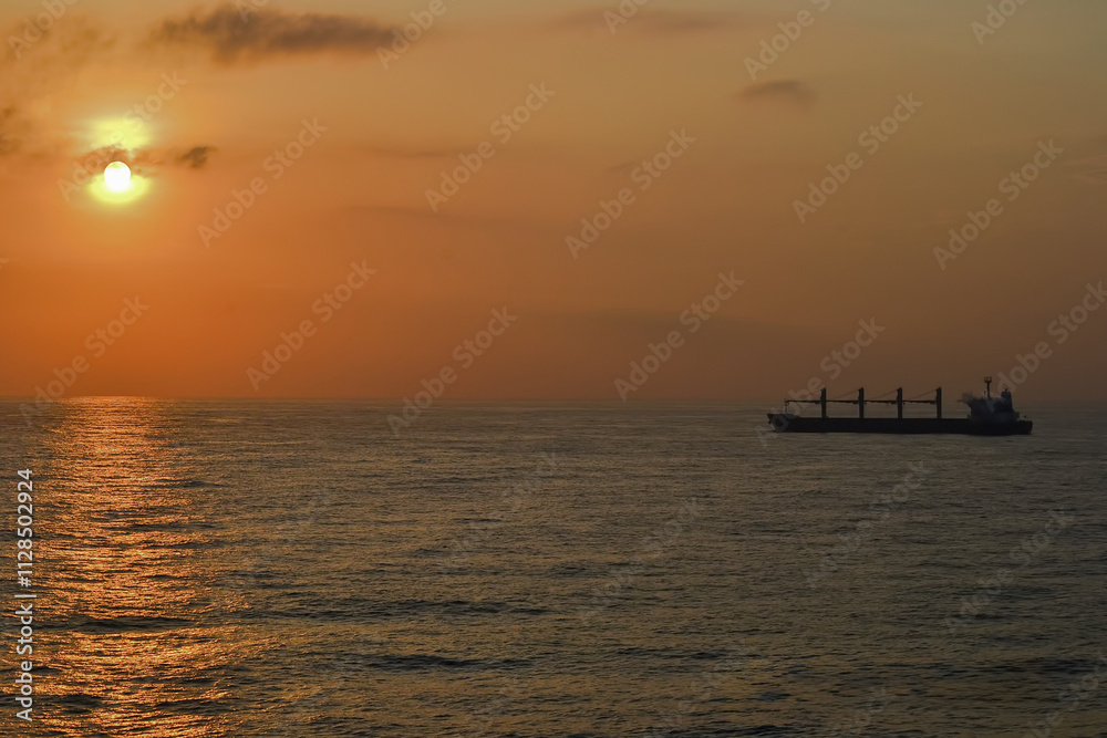 Serene Sunset Over Ocean with Cargo Ship Silhouette Serene Sunset Over Ocean with Cargo Ship Silhouette